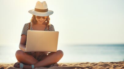 woman reads on laptop at beach